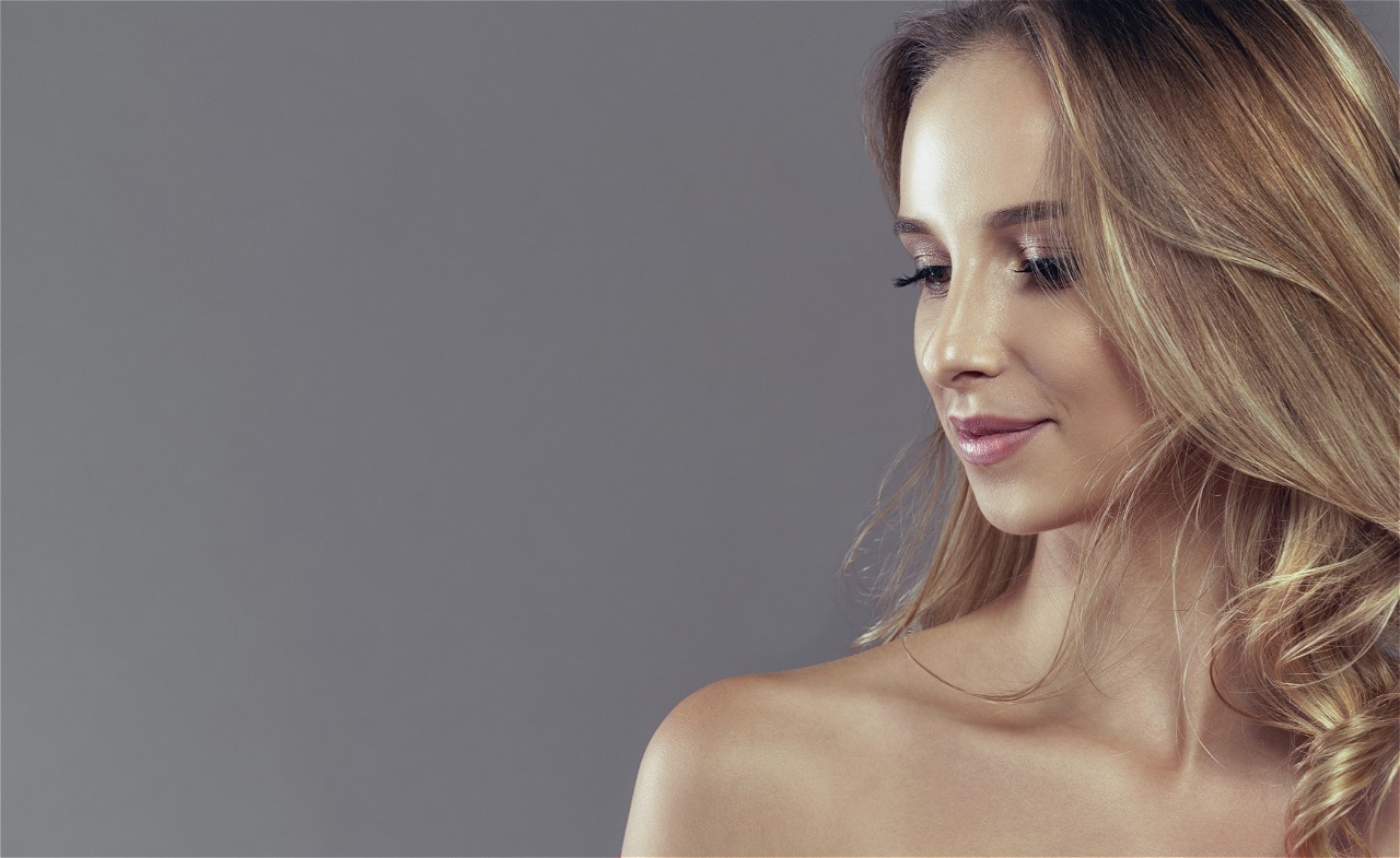 frau blickt lächelnd nach unten, Dr. Hädrich - Regenerative Ästhetische Medizin